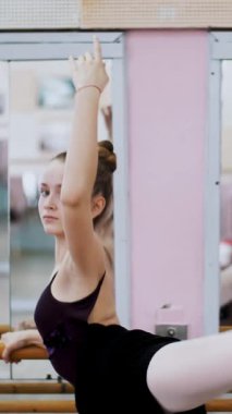 dans salonu, siyah tek parça streç giysi içinde genç balerin grand battement tutum gerçekleştirir, zarif, ayakta barre adlı bale sınıf aynada yakınındaki arkasında bacağını yukarı yükseltir..