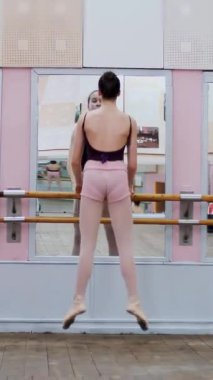 dans salonunda genç balerinler siyah tayt içinde pas soute, bale sınıf aynada, barre atlama gerçekleştirmek..