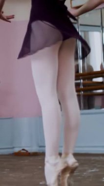 Dans salonunda, siyah taytlı genç balerin Glissade en tournant oynuyor, bale sınıfında zarifçe hareket ediyor.,.