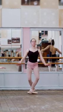 Dans salonunda, siyah taytlı genç balerinler dans eder, parmak uçlarında bale sınıfında aynanın yanında dikilirler...