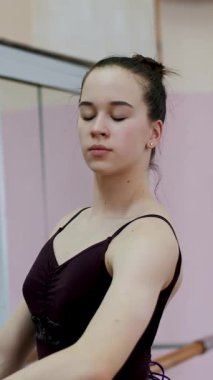 Mor tek parça streç giysi içinde genç balerin zarif barre adlı bale sınıf aynada yakın duran bir belirli bale egzersiz, arabesgue, gerçekleştirir..