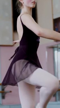 Mor tek parça streç giysi içinde genç balerin zarif belirli bale egzersizleri, beşinci pozisyonlarda bale sınıf pirouettes gerçekleştirir..