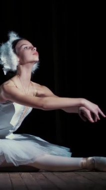 spot ışık, Sahne Alanı'ndaki eski tiyatro salonunun ışınları içinde. Beyaz Kuğu ve pointe ayakkabı, takım elbiseli genç balerinler dans zarif belirli bale hareket, bölümü de sütyen.