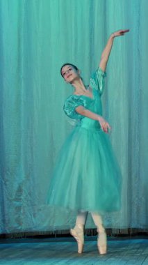 eski tiyatro salonu sahnesinde bale prova. Mavi bale ayakkabı, elbise ve pointe genç balerin dans ediyor zarif belirli bale hareket, Arabesk.