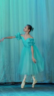 eski tiyatro salonu sahnesinde bale prova. Mavi bale ayakkabı, elbise ve pointe genç balerin dans ediyor zarif belirli bale hareket, Arabesk.