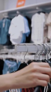 Alışverişe. Kıyafet alıyorum. Askıdaki giysiler. Müşteri giyim mağazasından alışveriş yapıyor. Kıyafet seçme süreci. Perakende. Satış. İndirim sezonu. mağaza..