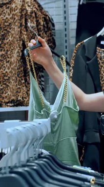 Alışverişe. Kıyafet alıyorum. Askıdaki giysiler. Alıcı giyim mağazasından alışveriş yapıyor. Kıyafet seçme süreci. Perakende. Satış. İndirim sezonu. mağaza..