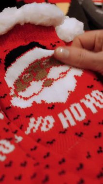 Noel hediyesi. Noel alışverişi, dekorasyon. Adil. Şenlik aksesuarları. Yakın plan. Kadın Noel hediyesi setini seçiyor, Noel Baba 'yla sıcak kırmızı çorapları, dükkanda. Mutlu Noeller ve mutlu yıllar. Alışveriş merkezi.