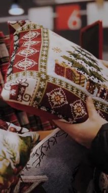 Noel alışverişi, dekorasyon, fuar. Noel dekoratif yastıkları. Yakın plan. Kadınlar Noel ziyafeti aksesuarlarını, dekoratif yastıkları dükkanda seçerler. Mutlu Noeller ve mutlu yıllar. Alışveriş merkezi.