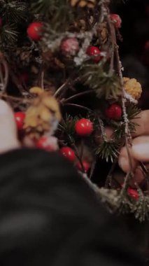 Noel alışverişi, dekorasyon, fuar. Yakın plan. Kadın dükkanda Noel için aksesuar seçiyor. Noel için süsleme olarak, kozalaklı bitkilerin yapay dalları.