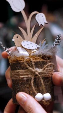 Paskalya indirimi. Yakın plan. Güzel bir Paskalya süslemesi tutan dişi eller, bir kuş, yumurta ve çiçeklerle kompozisyon. Paskalya dekoru alışverişi. Paskalya süsleri ve hediyeler dükkanda.,