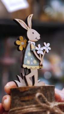 Paskalya panayırı. Yakın plan. Paskalya süslerini tutan kadın elleri. Paskalya tavşanının komik biblosu. Katolik Paskalyası için geleneksel Avrupa dekorasyonu