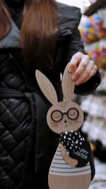 Paskalya panayırı. Yakın plan. Paskalya süslerini tutan kadın elleri. Paskalya tavşanlarının komik figürleri. Katolik Paskalyası için geleneksel Avrupa dekorasyonu