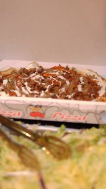 Şef şu malzemeleri kullanarak pizza hazırlıyor: lavaş, et, sos, sebze, salatalık, soğan, lahana, baharatlı biber, patates, yeşillik, havuç
