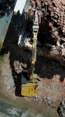 Havadan bakıldığında, yıkılan bir binanın ortasında, kentsel yenileme ve inşaat sürecini gösteren bir kazıcı görülüyor. Şehir kalkınmasının dinamik doğasını yakalayan enkaz, ağır makineleri çevrelemektedir.