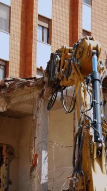 BIELLA, İtalya, 25 Nisan 2024: Güçlü bir hidrolik kazıcı kısmen yıkılmış bir binanın yıkımı ile meşgul, bir şehir bölgesinde devam eden kentsel yeniden yapılanma
