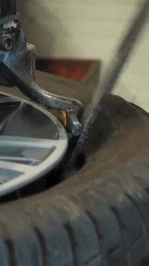 Lastik uyumu. Tekerleği sökmek için hidrolik ya da mekanik baskı kullanan bir tamirci. Tamirci, profesyonel ekipman kullanarak lastiği jantından çıkarıyor.