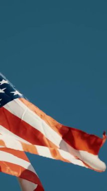 Mavi arka planda dalgalanan Amerikan Bayrakları. Amerikan Bayrağı. Mavi gökyüzünün önünde Amerika Birleşik Devletleri 'nin ünlü bayrağını sallayarak.