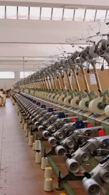 İplik üretimi. Tekstil fabrikası. Dönen yapım. İplik yapma süreci. Tekstil fabrikası ekipmanı. Fabrika makineleri makaraları ya da pamuklu ya da yün ipliklerle bobinleri geri sarıyor.