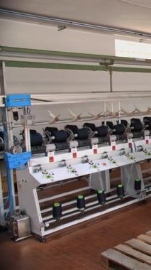 İplik üretimi. Tekstil fabrikası. Dönen yapım. İplik yapma süreci. Tekstil fabrikası ekipmanı. Fabrika makineleri makaraları ya da pamuklu ya da yün ipliklerle bobinleri geri sarıyor.