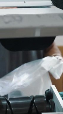 Bir işçi iplik makaraları taşır. Tekstil fabrikası ekipmanı. Tekstil fabrikası. Dönen yapım. İplik yapma süreci. Fabrika makineleri makaraları ya da pamuklu ya da yün ipliklerle bobinleri geri sarıyor.