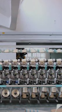 Tekstil fabrikası. İplik yapma süreci. İplik üretimi. Dönen yapım. Tekstil fabrikası ekipmanı. Fabrika makineleri makaraları ya da pamuklu ya da yün ipliklerle bobinleri geri sarıyor.