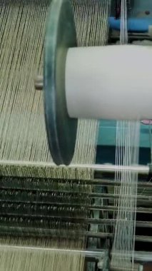 Tekstil fabrikası üretim ekipmanları çalışıyor. Yakın plan. Beyaz iplikli büyük bir makara. Dokuma mekanizması ipliklerden kumaş üretir. Tekstil endüstrisi. Dokuma fabrikası. kumaş üretimi.