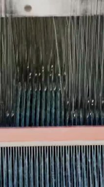 Tekstil fabrikası. Dokuma. Çalışan otomatikleştirilmiş dokuma makinelerinin yakın çekim görüntüleri. Tekstil fabrikası ekipmanı. Dokuma kumaşı endüstriyel bir makine tarafından serbest bırakılıyor..