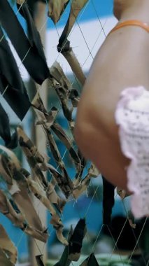 Kamuflaj ağı. Gönüllü. Yakın plan. Gönüllü asker ordunun askeri ihtiyaçları için yeşil ya da haki rengi kumaşlardan oluşan bir kamuflaj ağı örüyor. Ukrayna 'da savaş.