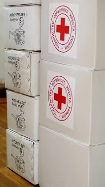 Kızıl Haç. Hayır kurumu. Gönüllü Depo. İnsani yardım paketleri kırmızı haç amblemli karton kutularda. Mülteciler ve göçmenler için sosyal bağışlar.