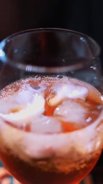 Kokteyl. Kokteyl hazırlıyorum. Barmen kokteyl yapar. Yakın plan. Barmen nazikçe bardağa portakal dilimi koyar, içki ve buz da tezgahın üzerinde. Farklı malzemelerden oluşan bir kokteyl. boğuk ışık.