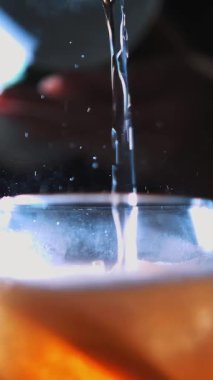 Kokteyl. Gazoz köpükleri. Kokteyl yapıyorum. Yakın plan. Barmen nazikçe gazoz köpüklü karbonatlı içeceği kokteyl ile bardağa doldurur. boğuk ışık arkaplanı.