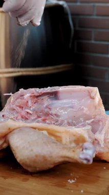 Korkak. Yemek pişirmek. Yakın plan. Şef taze çiğ tavuğu baharat ve tuz ile kesme tahtasına sürterek serpiyor. Şef pişirmek için tavuk pişirir.