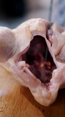 Korkak. Şef yemek hazırlıyor. Yakın plan. Üst Manzara. Kasap taze çiğ bir tavuğu kesme tahtasıyla parçalara ayırıyor. Şef baharatlı tavuk pişiriyor.