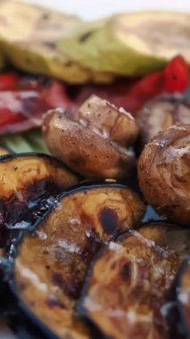 Izgara sebze. Yemek pişirmek. Yakın plan. Döndürme. Izgarada kızartılmış, tabakta barbekü sebzeleri var. Vejetaryen yemeği ve sağlıklı yemek.