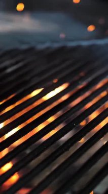 Izgara yap. Arka planda boş siyah ızgara ızgarası. Restoran mutfağında büyük ızgara çeviriyor. Izgaranın altından sıcak, buharlı, parlayan ateş görülebilir. Barbekü.