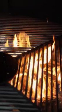 Izgara yap. Arka planda boş siyah ızgara ızgarası. Restoran mutfağında büyük ızgara çeviriyor. Izgaranın altından sıcak, buharlı, parlayan ateş görülebilir. Barbekü.