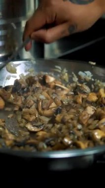 Yemek pişirmek. Kızarmış mantar. Yakın plan. Kızarmış mantar. Aşçı, restoranın mutfağındaki tavada soğanlı mantar kızartıyor. Vejetaryen yemeği..