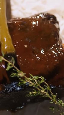 Izgara et servisi. Yemek pişirmek. Yakın plan. Sosu, güzel kokulu otları ve baharatları olan lezzetli bir et parçası servis edilir. Restoran. Sanat aşçılığı. Barbekü.