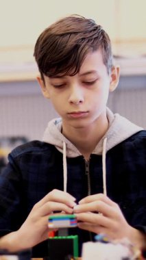 12 yaşında, çocuk oynar Tasarımcısı küpleri, tabaklar, devreler, teller. küçük bir mucit robotlar, makineleri tasarımcı farklı yerlerinden oluşturur