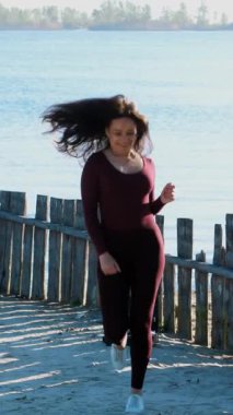 Yazın, nehir kıyısında, sahilde. Şafakta, güzel bir kadın sanatçı, dar bir takım elbise içinde, dans ediyor, zıplıyor. Yakında bir resim ve şövale var..