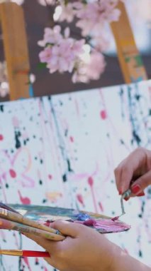 çiçeklenme içinde beyaz elbiseli güzel kadın ressam bahar elma bahçesi, o boyalar Palet üzerindeki özel küçük spatula ile karışımları. Sanatçı boya çiçek resim