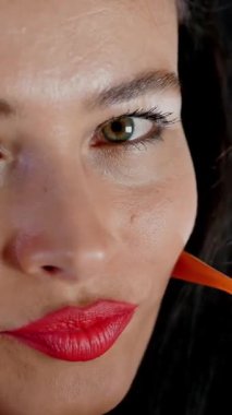 Kırmızı dudaklı esmer bir kadının portresi şık gözlük ve gözlük takan ve stüdyoda kameraya bakan. koyu gri arkaplan.