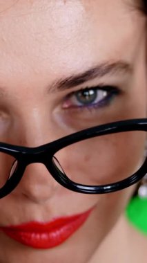 Kırmızı dudaklı esmer bir kadının portresi, şık gözlüklü, gözlüklü, eğlenceli hareketler yapan, kameraya bakan, stüdyoda poz veren. yeşil arka plan, kromeakey.