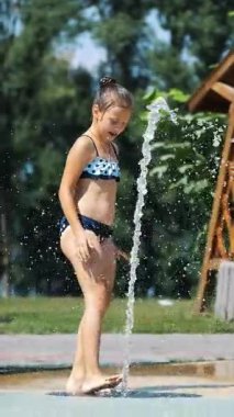 gülümseyen, mutlu sekiz yaşındaki kız sokak şehir Çeşme, açık havada, su sıçramalarına, eğleniyor park, yaz, tatil sırasında sıcak güneşli gün mayo.