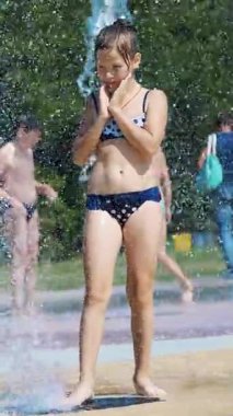 gülümseyen, mutlu sekiz yaşındaki kız sokak şehir Çeşme, açık havada, su sıçramalarına, eğleniyor park, yaz, tatil sırasında sıcak güneşli gün mayo.