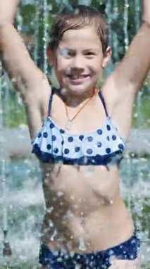 gülümseyen, mutlu sekiz yaşındaki kız sokak şehir Çeşme, açık havada, su sıçramalarına, eğleniyor park, yaz, tatil sırasında sıcak güneşli gün mayo.