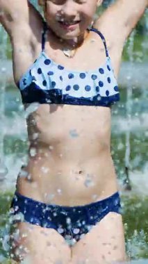 gülümseyen, mutlu sekiz yaşındaki kız eğleniyor şehir Çeşme, açık havada, park, yaz, tatil sırasında sıcak gün mayo.