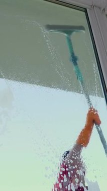 Görünümü penceresinden, gülümseyen beyaz güzel kadın, eldiven, Temizleme, köpük camına bir sürü özel paspas tarafından pencere yıkama. Temizleme Servisi.