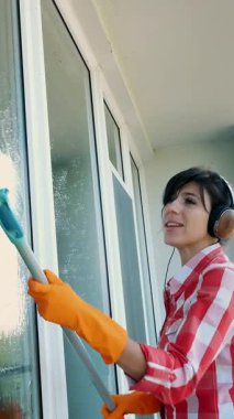 kulaklık, eldiven, güzel kadın, şarkı müzik tarafından özel paspas pencere yıkama, onun iş zevk Temizleme. hizmet veya ev kadını temizlik işçisi